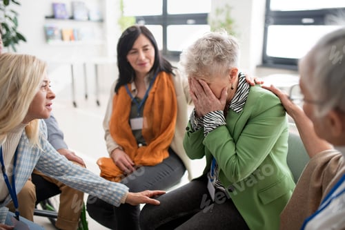 Preview: Group of senior people sitting in circle during therapy session, consoling depressed woman.