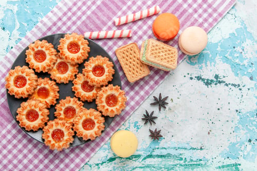 Preview: top view delicious little cookies with orange jam macarons and waffles on blue desk cookie biscuit