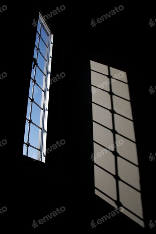 Preview: The light from the windows shines on the wall in the dark room.
