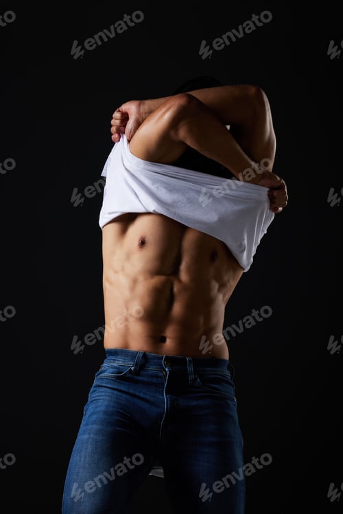 Preview: Fitness, body and man remove tshirt for exercise, wellness and workout in studio on black backgroun