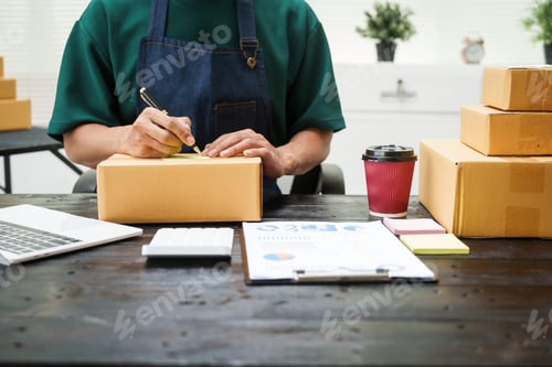 Preview: A man is working at his desk, preparing parcel boxes for shipment. He checks packs items carefully