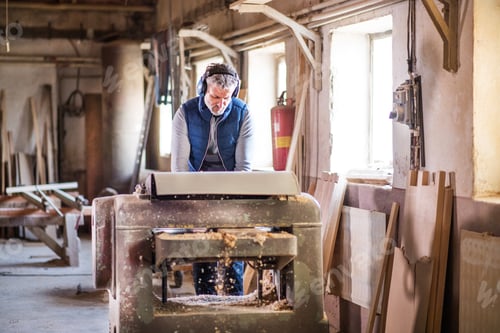 Preview: A man worker in the carpentry workshop, working with wood.