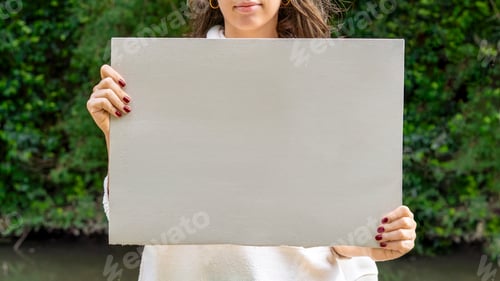 Preview: Woman holding a blank sign by the river, ready for a message