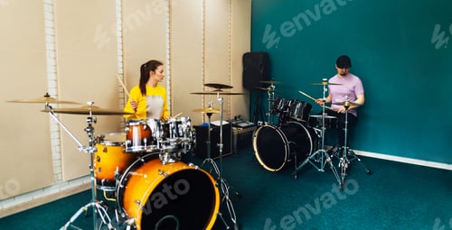 Preview: The girl and the guy are sitting at the drum kits. Music group rehearsal.