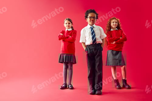 Preview: Group Of Elementary School Pupils Wearing Uniform Folding Arms Against Red Studio Background