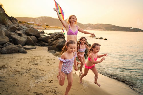 Preview: Joyful family playing together at the beach during sunset