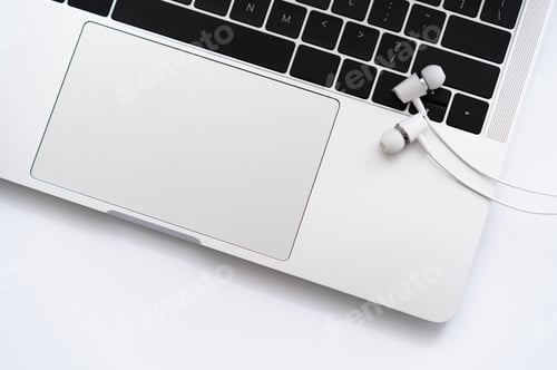 Preview: top view of white wired earphones near laptop on white