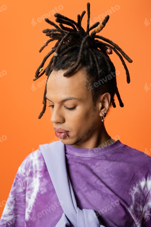 Preview: portrait of multiracial man with dreadlocks and piercing isolated on orange