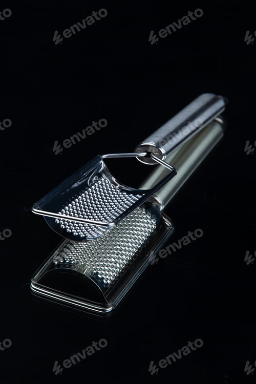 Preview: Vertical view of stainless kitchen cheese grater on isolated black background with free space