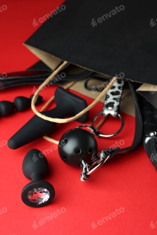 Preview: Shopping bag and different sex toys on red background