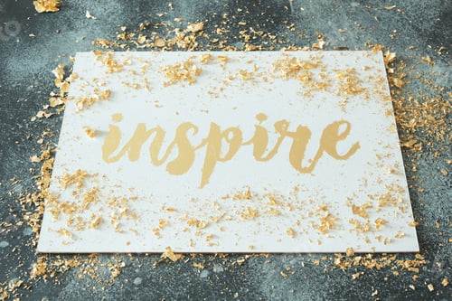 Preview: Inspire. Motivating lettering on white board. Handmade creativity. Gold letters. Gilding.