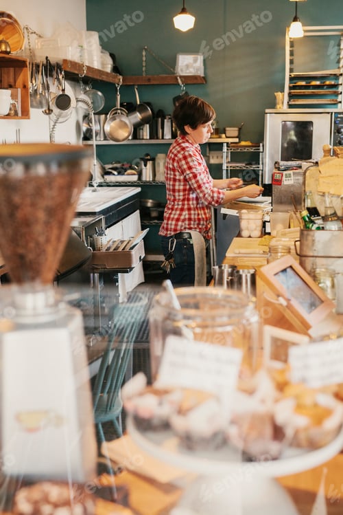 Preview: A woman in a plaid shirt working behind the counter in a coffee shop.