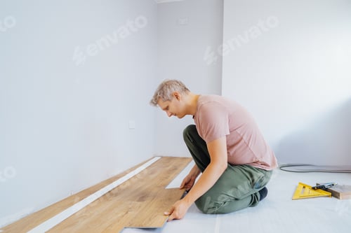 Preview: Young handyman installing flooring in new Home by his own. Doing measurements, calculating