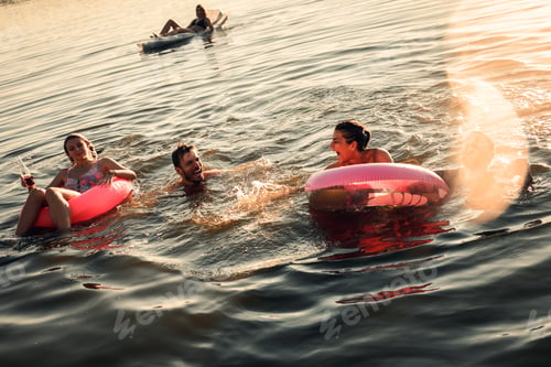 Preview: Group of young friends having fun and enjoying a summer day swimming at the lake.
