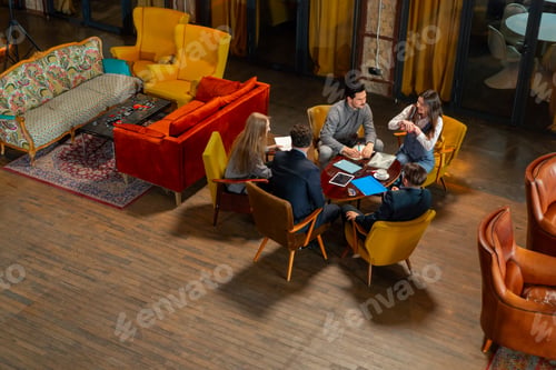 Preview: top shot in large beautiful hall office employees sitting on yellow chairs discuss a deal