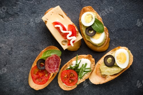 Preview: Open faced sandwich canape or crostini on dark stone background closeup. Top view.