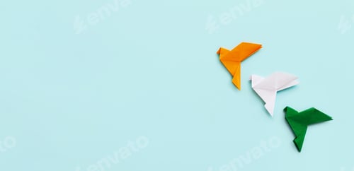 Preview: Three paper origami pigeons orange, white green go up on blue light background, banner, copy space