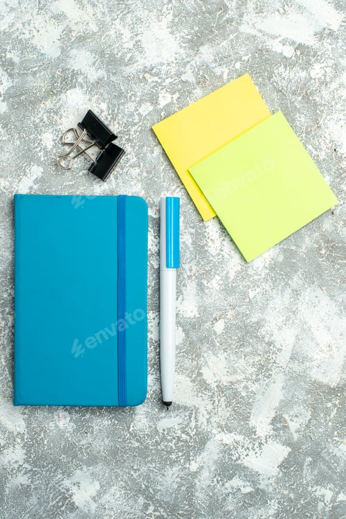 Preview: Vertical view of closed blue notebook and pen colorful note papers on white background