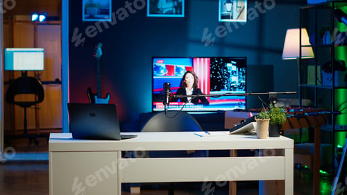 Preview: Notebook device sitting on table, news broadcast running on TV in background