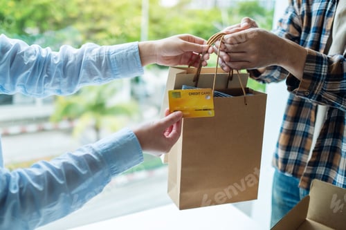 Preview: A woman receive shopping bags form delivery man and using a credit card for payment