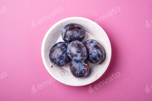 Preview: Fresh ripe plum fruits in white wooden bowl on pink minimal background