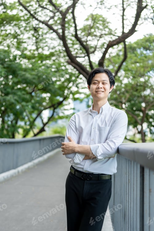 Preview: Portrait of Asian young businessman standing outdoors in public park.