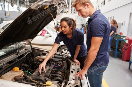 Preview: Two apprentice mechanics looking at the engine in a car