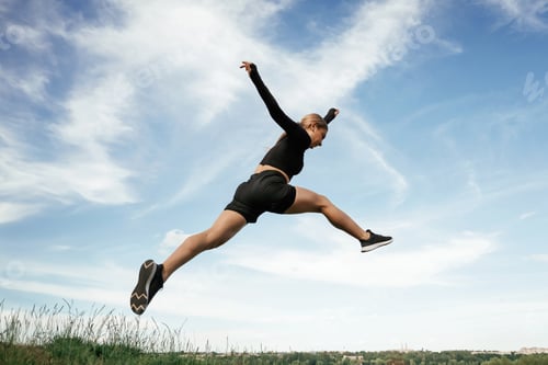 Preview: Jumping against the sky. Beautiful fitness woman in sport clothes is outdoors