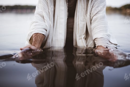 Preview: Closeup shot of a male wearing a biblical robe with his hands gathering water