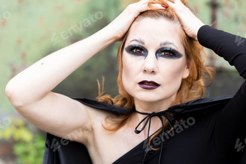 Preview: Attractive beautiful woman with a lantern cooking potion in a Halloween costume and scary make-up