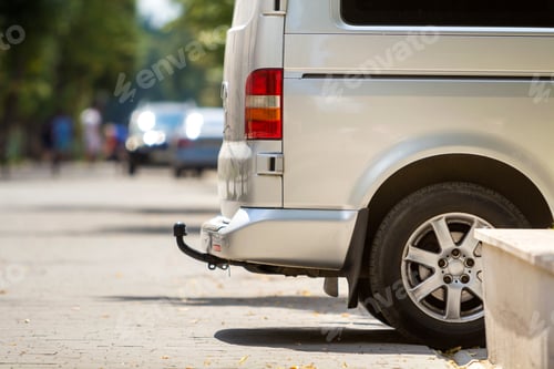Preview: Close-up side view detail of silver passenger medium size luxury minibus van with tow-bar parked on