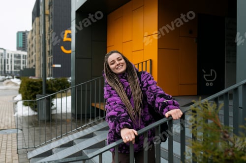 Vista previa: Lifestyle concept. A young woman with dreadlocks and piercings stands at the entrance to an orange