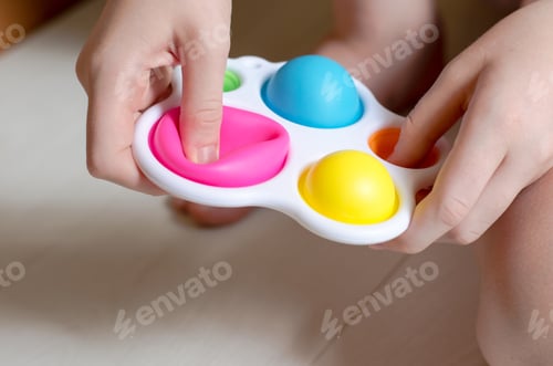 Preview: Close-up of a simple dimple in the hands of a child. A child plays with a modern toy simple dimple