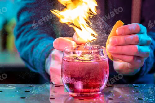 Preview: Close up of alcoholic cocktail, beverage, drink in multicolored neon light with fire flames setting