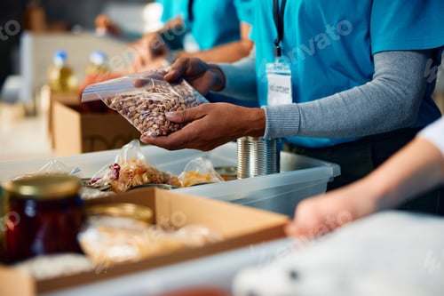 Preview: Close up of woman packing donation boxes while volunteering at food bank.