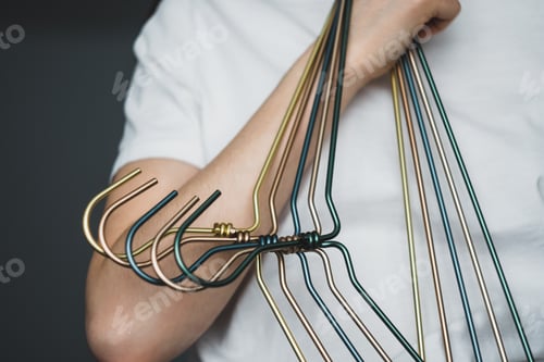 Preview: Woman holds metal clothes hangers in hands, at home in the dressing room.