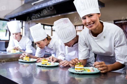 Preview: Group of chefs garnishing delicious desserts in a plate