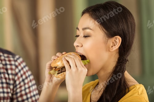 Preview: portrait of young asian girl eating tasty burger