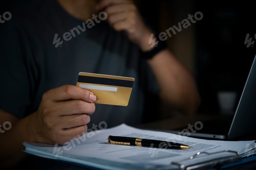 Preview: Man holds credit card online payment or financial transaction, with a laptop