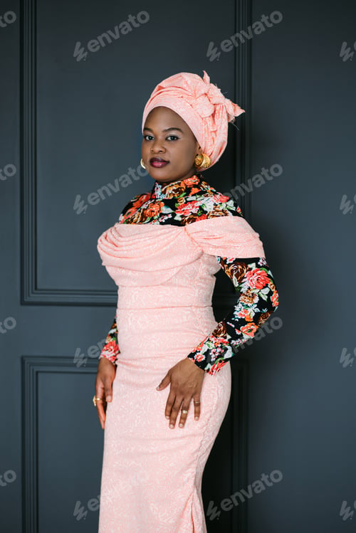 Preview: African female model in stylish pink dress, bright blouse and headscarf, posing at studio