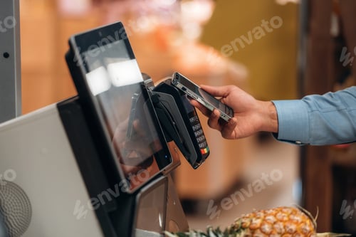 Preview: Close up view of man customer that is paying for products by credit card in grocery store
