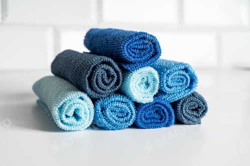 Preview: Colorful microfiber towels in the form of pyramid on a white table. Cleaning and housekeeping