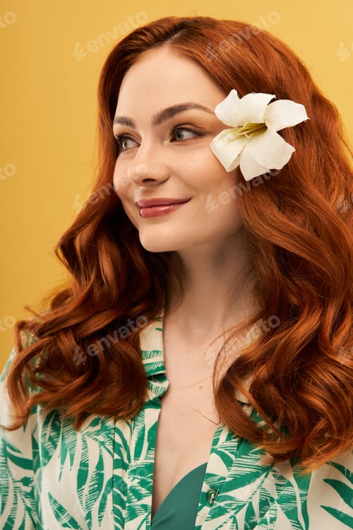 Preview: Bright and cheerful woman with flowing red hair and flower accessory enjoying a sunny moment