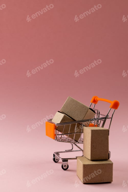 Preview: Composition of shopping cart with boxes on pink background