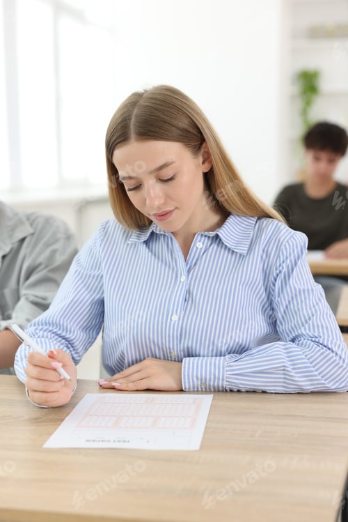 Preview: Students taking exam at wooden table indoors, selective focus