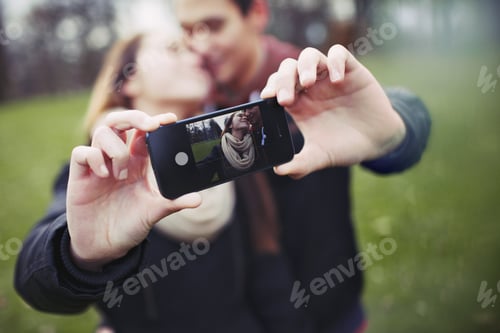 Preview: Romantic teenage couple taking self portrait with cell phone