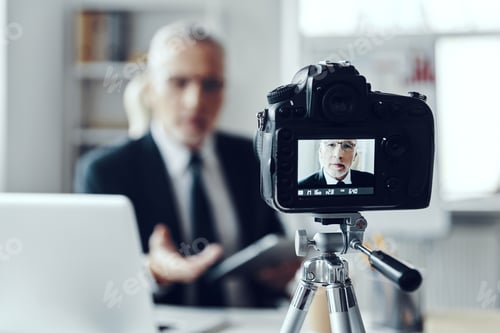 Preview: Senior man in elegant business suit using digital tablet while making social media video