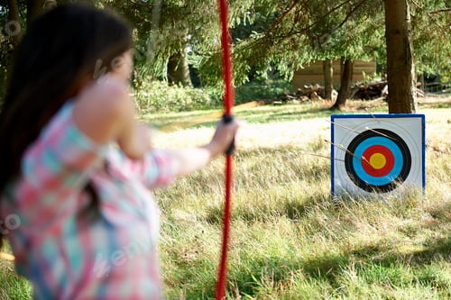 Preview: Rear view of teenage girl practicing archery with target