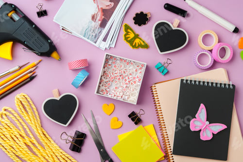 Preview: Crafting supplies arranged on a pink background, including glue gun, scissors, and decorative items