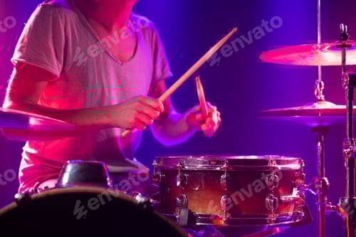 Preview: Drummer Playing Drums on Stage with Purple Lighting